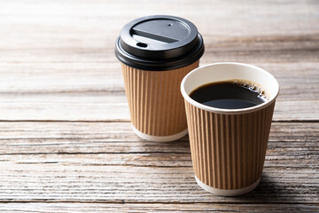 A paper cup of coffee on an old wooden background