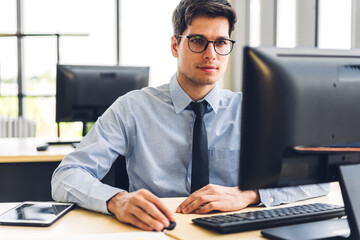 Handsome confident businessman relaxing looking at technology of desktop computer monitor while sitting on chair.Young creative coworkers business people working and typing on keyboard at office