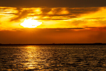 Beautiful sunset with the sun on the horizon reflecting the golden light in the lake water