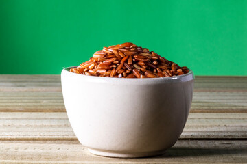 red rice on glass bowl isolated on wooden table in Brazil
