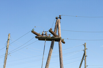 Electric Power line with wooden poles against blue sky background. Birds are sitting on a power line