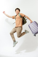 Excited happy young Asian man tourist with luggage jumping isolated on white background