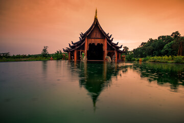 Naklejka premium The background of the Wat Pa Kham Charoen is a beautiful old church with a Buddhist statue and a tree-lined temple, with tourists and travelers always making merit in Udon Thani, Thailand.