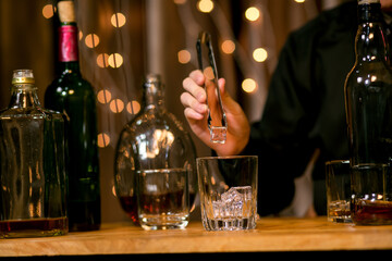 Waitress man standing pours whiskey into a glass 
