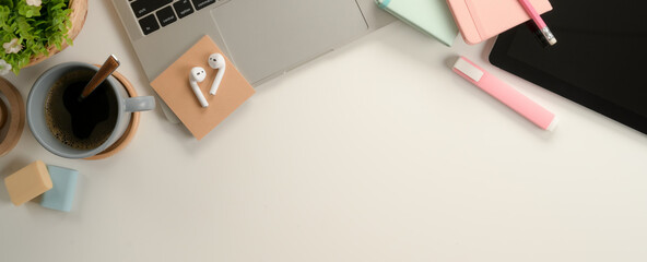 Feminine study table with laptop, tablet, stationery, coffee cup and copy space on white desk