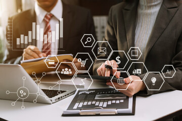 Business documents on office table with smart phone and calculator digital tablet and graph business with social network diagram and two colleagues discussing data working in the office
