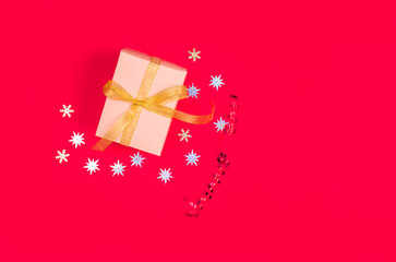 Bright red background with a festive box and gift, gold ribbon, shiny stars