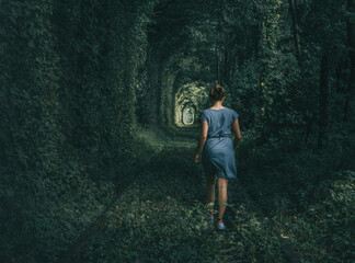 Young woman walking through a tunnel of love  an abandoned rail track in Ukraine. 