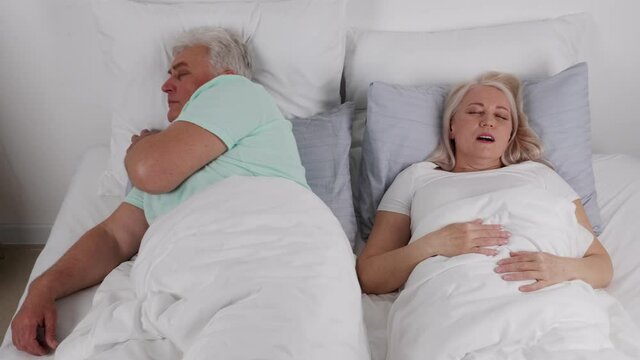 Mature man in bed with snoring wife