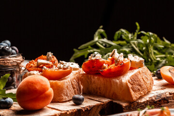 Delicious Toast with soft dor blue cheese, fresh juicy peach, blueberry and honey on wooden board. Healthy summer appetizer or snack, place for text