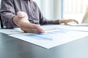 The hands of a male businessman are analyzing and calculating the annual income and expenses in a financial graph that shows results To summarize balances overall in office