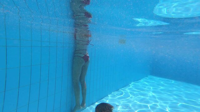young man rising to the surface of the pool and kissing his girlfriend
