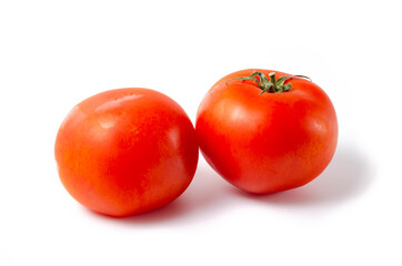 Two red tomatoes are seen tail green on a white background front and top view.