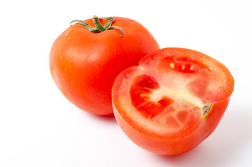Two red tomatoes are seen tail green on a white background front and top view. One tomato is whole, the other is cut, in section