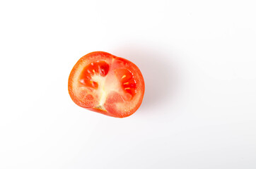 One red tomato in a cut on a white plate front and top view.