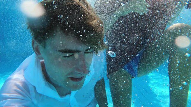 young couple diving into the swimming pool dressed - relax, holiday