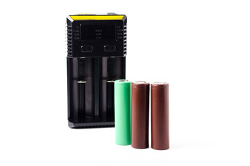 Fototapeta premium A black charger for two 18650 batteries. A green and brown 18650 battery on a white background next to the discharge, on charging. Male hand puts the battery on charge