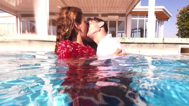 young dressed couple kissing passionately in the pool