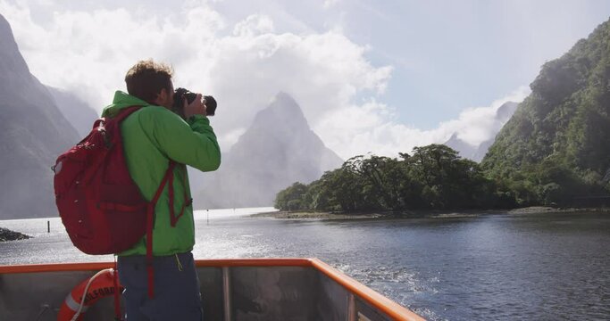 Landscape nature travel photographer tourist taking photo of Milford Sound and Mitre Peak in Fiordland National Park, New Zealand while on cruise ship boat tour.