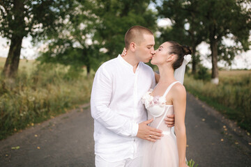 Young and beautiful bride with handsome groom hug each other kiss and smile. Portrait of happy wedding couple