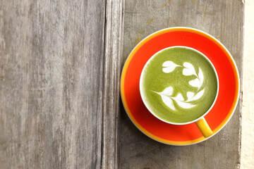 A cup of green tea matcha latte on wooden background                                                                                                                            