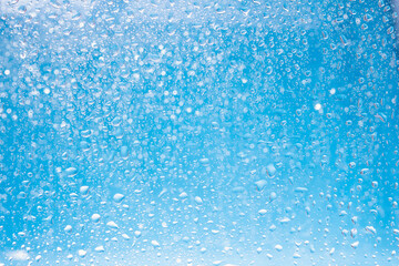 Fototapeta na wymiar Blue water drops background. Blue water drops on a boat glass background.
