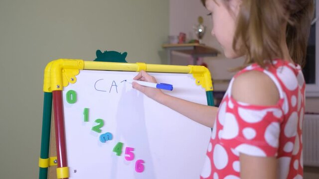 Child Girl Using Magnet Board To Learn Letters And Numbers At Home