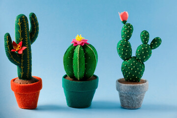 The set of cute toy cactuses  are on the blue background. The concept of needlework, small toys for children, plants that do not require maintenance.