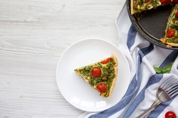 A Piece of Homemade Spinach Quiche on a white plate, top view. Flat lay, overhead, from above. Copy space.