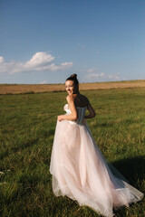 Fototapeta na wymiar Fashion posing of gorgeous bride. Elegant bride walking in field in wedding dress