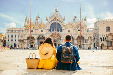couple sitting on the ground enjoying the view of saint marco square Venice Italy - obrazy, fototapety, plakaty