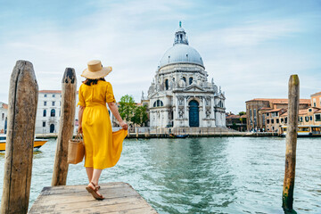 woman in yellow summer dress walking by Venice looking at grand canal
