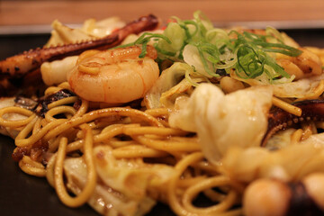 Japanese fried noodles with prawn, squid, cabbage and topped with some red sliced pickled ginger and green onion