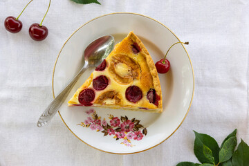 Piece of fruit cake with sour cream filling, apricots and cherries on a white plate