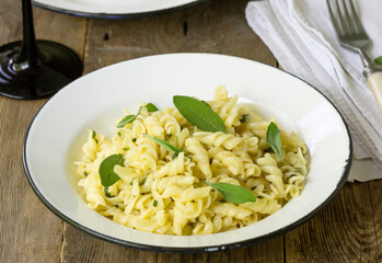 Fusilli pasta with sage leaves in a white bowl
