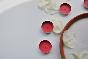 Beautiful spa composition of white rose petals and candles on white background.