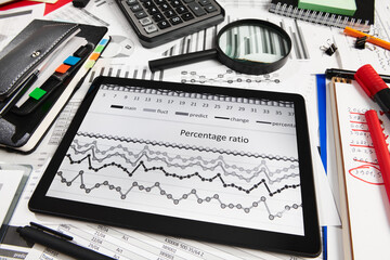 Obraz premium Top view of office employee's desk - work with tablet pc computer and financial reports, analysis and accounting, tables and graphs, various office items for bookkeeping