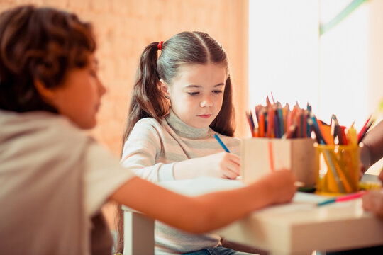 Concentrated girl drawind with color pencils during the art class
