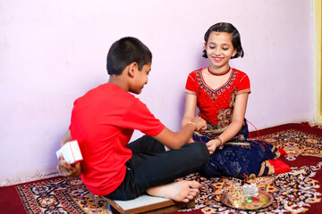 Young indian brother and sister celebrating raksha bandhan festival at home