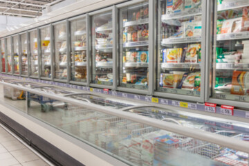 Glass showcases with frozen foods in a large supermarket. Blurred.
