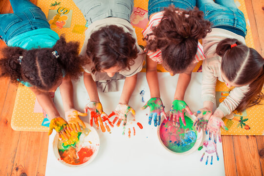 Children painting with their hands during the art class