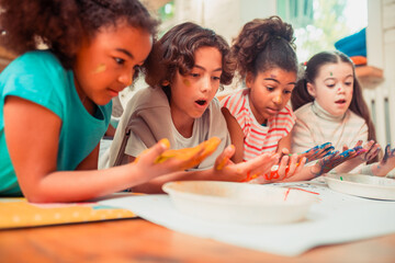 Surprised children painting with their hands during the art class