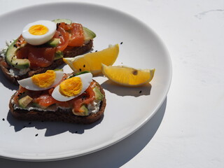 Healthy breakfast.Whole grain bread sandwiches with cream cheese, egg, avocado and salmon fish on a white wooden background. View from above.