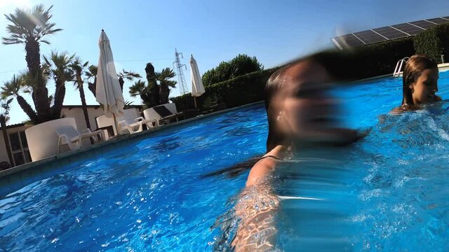  summer games -two girls holding hands diving underwater in the pool