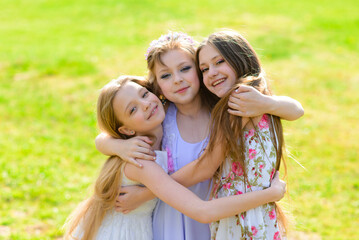 Three beautiful girls in retro dresses for a walk in a flowered garden. The idea and concept of a friendly family and a happy childhood.