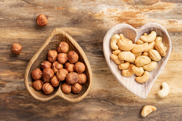 Peeled hazelnuts and cashews in wooden plates on a natural wooden background.