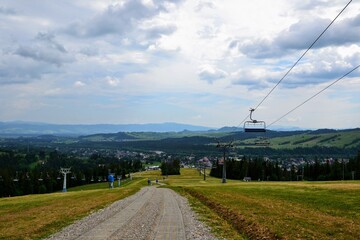 Fototapeta na wymiar Alpine ski lift (or chairlift) going from Bialka Tarzanska to the station at the top of the mountain Kotelnica. Summer in Podhale, Poland, Europe