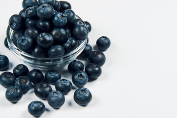 Freshly juicy picked blueberries in glass bowl isolated on white background. Top view. Selective focus. 