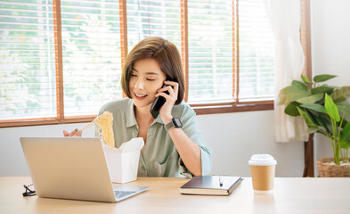 Portrait of young asian woman enjoying chinese food in office lunch break, female employee holding...