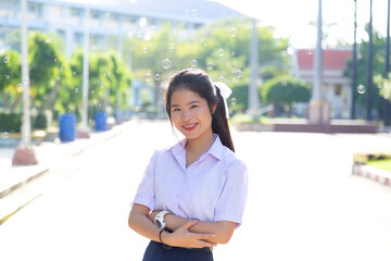 Asian Schoolgirl in a white dress is going to school. Asian student in a white school uniform standing on the road to prepare to go to school.